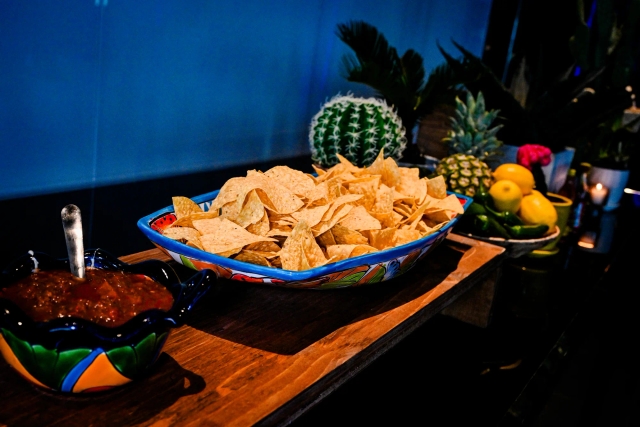 Large bowl of nachos next to a medium bowl of salsa.