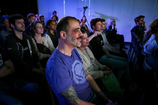 Audience members listening to Sarah Rainsberger speaking on stage.