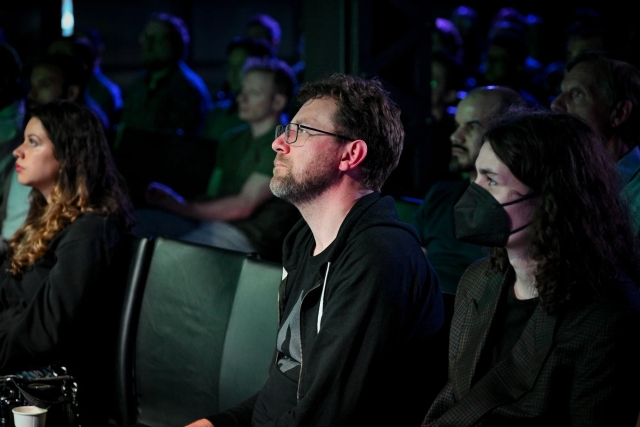 Closeup of Matt Kane gazing intently at Fred K. Schott as he speaks on stage.