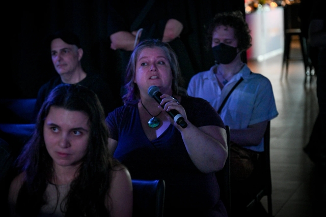 An audience member holding a microphone, asking keynote speakers a question.