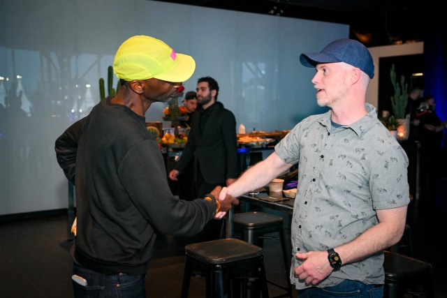 Two male guests shake hands.